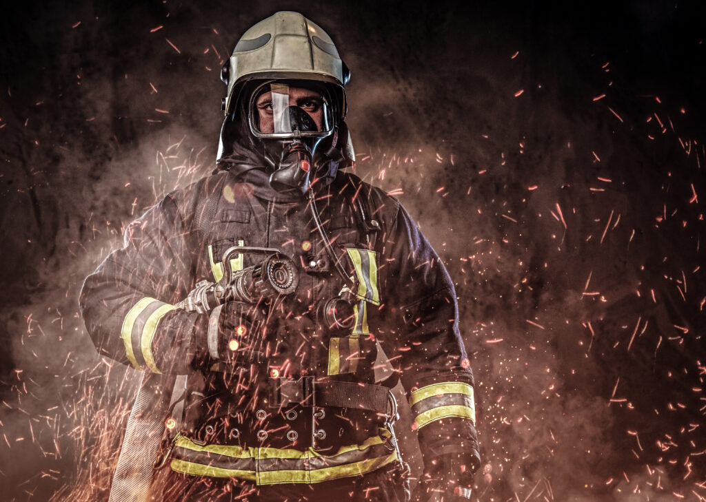 Bombero profesional vestido uniforme mascara oxigeno parado chispas fuego humo sobre fondo oscuro
