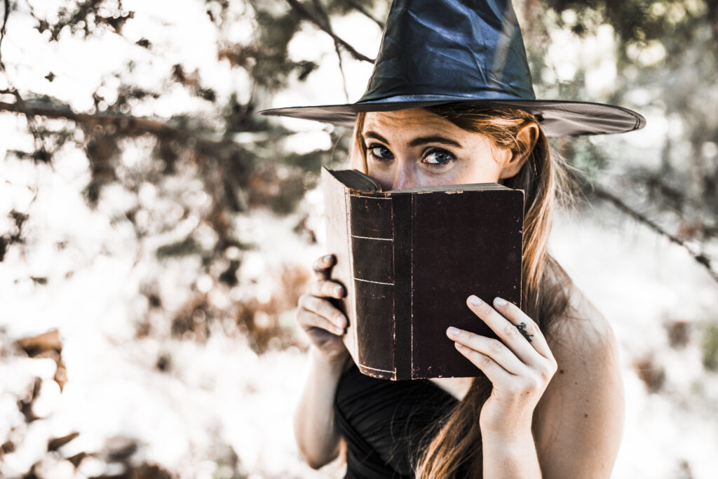 Mujer joven sombrero mago que cierra boca libro bosque