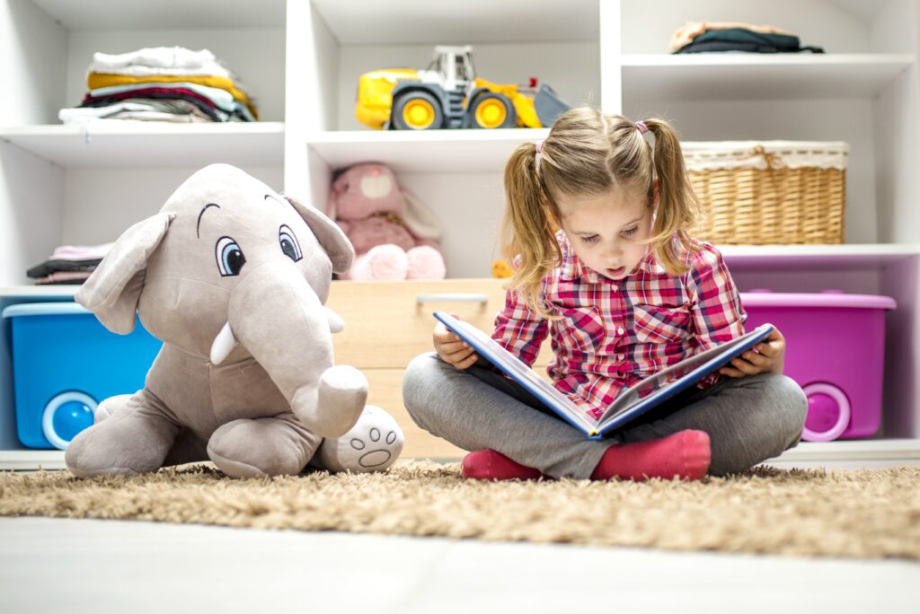 Adorable nina sentada alfombra leyendo libro su elefante peluche